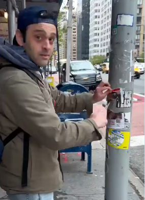 Image of Charles Gelman ripping down hostage posters