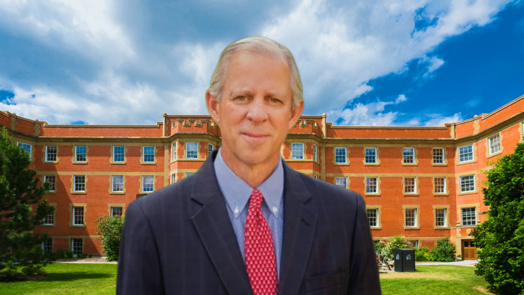 University of Arizona President Robert Robbins stands in front of a red-brick campus building under a partly cloudy sky, symbolizing university leadership amid rising campus tensions over Israel-Hamas protests. 